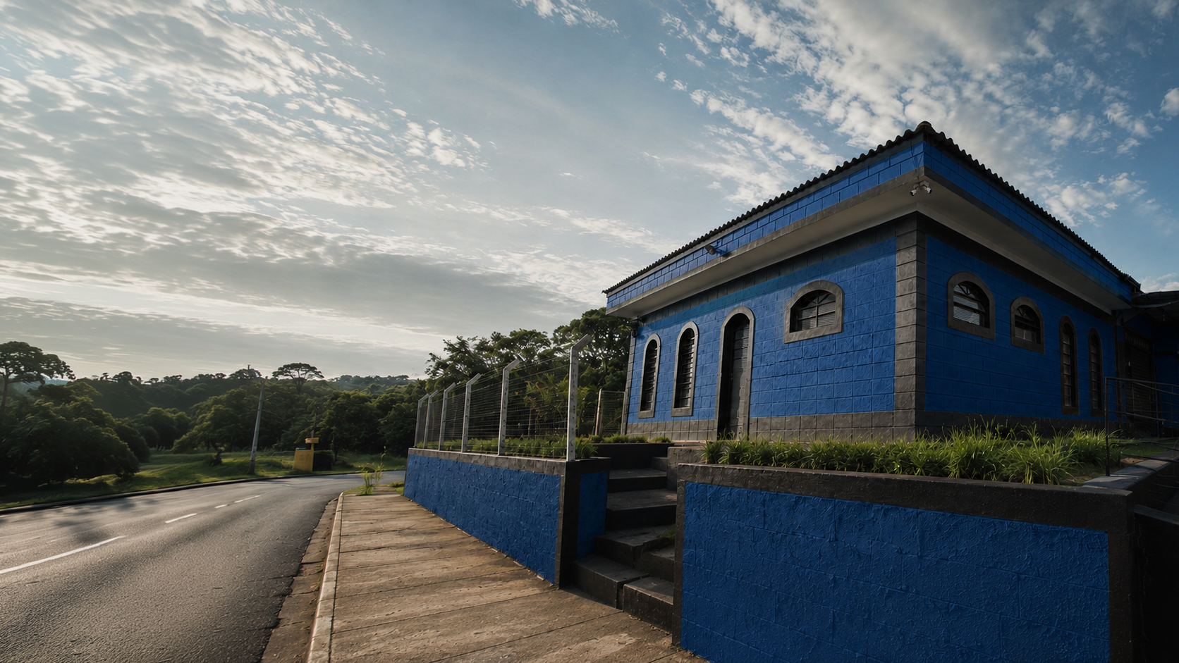 Fachada lateral da Metalúrgica Primer · prédio azul, estrada e horizonte